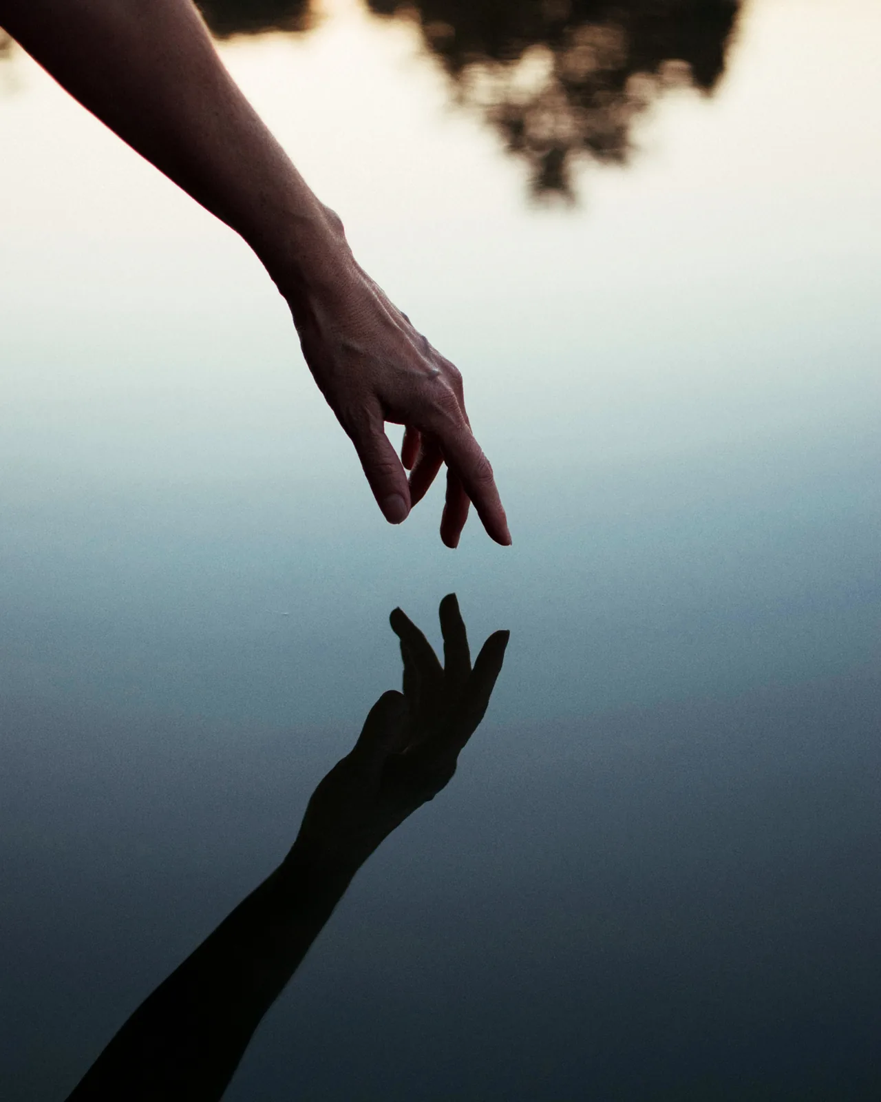 A hand about to touch still water